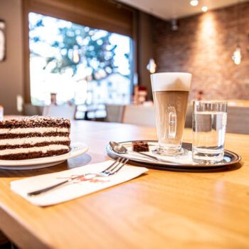 Ein Stück Schwarzwäldertorte und ein Latte Macchiato stehen auf Tisch im Café Dietikon